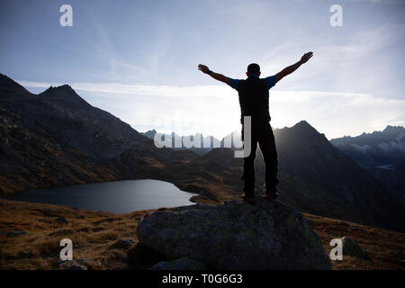 Randonneur est debout sur un rocher avec les mains et profiter de le lever du soleil dans les Alpes en Suisse Banque D'Images