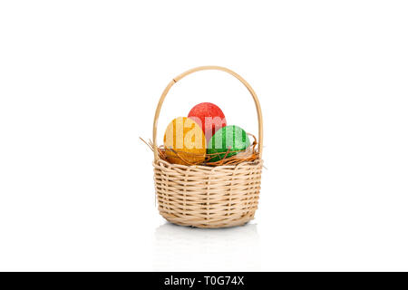 Les oeufs de Pâques colorés avec des paillettes dans le nid en bois isolé sur fond blanc sur le panier. Joyeuses Pâques Banque D'Images