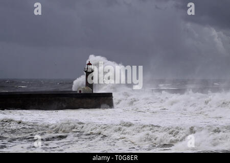 Big White vagues de Piers et phare contre une sombre tempête ciel nuageux. La bouche de la rivière Douro, Porto, Portugal. Banque D'Images