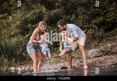 Une jeune famille avec deux enfants enfant passer du temps à l'extérieur de la rivière en été, d'avoir du plaisir. Banque D'Images