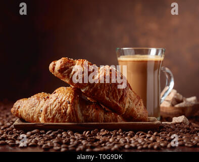 Latte Café et croissant sur une table avec les grains de café. Banque D'Images