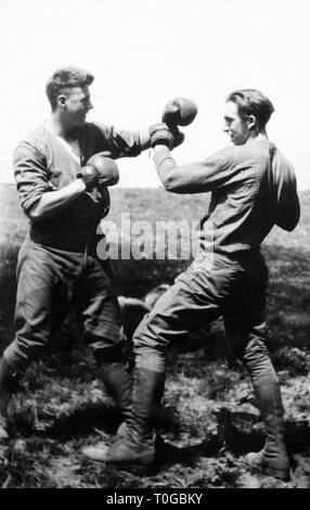 Deux jeunes hommes s'engagent dans un match de boxe dans un champ, ca. L'année 1930. Banque D'Images