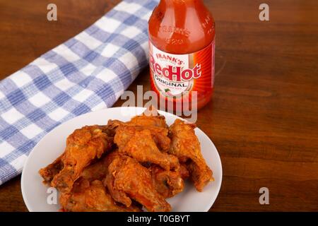 ATLANTA, GÉORGIE - 19 Avril 2017 : Ailes de poulet Buffalo sur une plaque blanche avec une bouteille de Frank's Red Hot Sauce en arrière-plan Banque D'Images