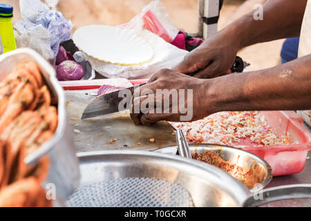 Main d'un homme de la mer la cuisine Cook à l'extérieur dans un marché de rue à Colombo, Sri Lanka. Banque D'Images