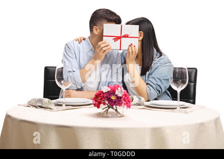 Les jeunes hommes et femmes de se cacher derrière une boîte-cadeau dans un restaurant tableau isolé sur fond blanc Banque D'Images