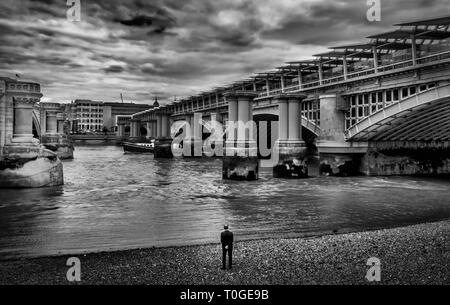 L'homme sur la berge de la Tamise par le pont de chemin de fer de Blackfriars, Londres UK Banque D'Images