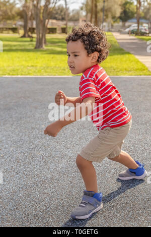 Le petit garçon commence à courir. Il voit certains enfants au parc et fait courir vers eux. Banque D'Images