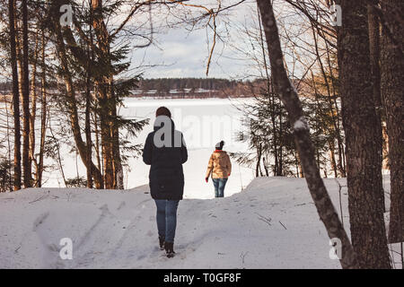 Deux jeunes filles à pied à travers la forêt d'hiver à un lac gelé. Un merveilleux changement de saison, l'arrivée du printemps, tout vient à la vie avec la FIRS Banque D'Images