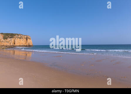 Plage de sable de l'Océan Atlantique d'une réflexion au coucher du soleil, Algarve, Portugal. Scenic cliff et marée basse rouleaux des vagues sur la plage. Banque D'Images