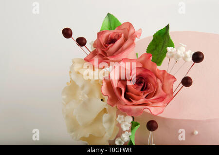 Gâteau décoré avec des fleurs et des feuilles de rose rose sur fond blanc. Banque D'Images