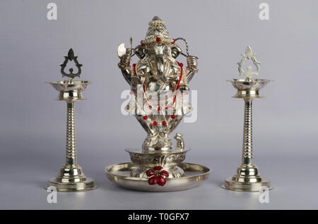 L'argent Le Dieu Ganesh idol mis sur fond blanc avec deux lampes traditionnelles indiennes Samai ou gardé sur les deux côtés. Banque D'Images