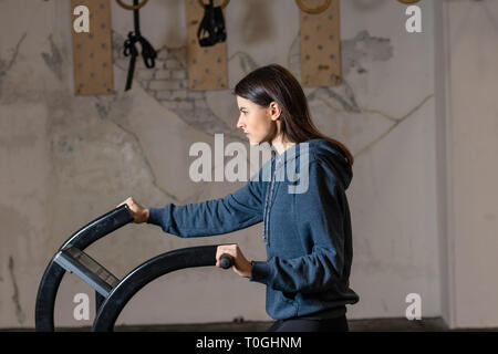 La jeune fille est engagée sur une bicyclette d'exercice crossfit dans la salle de sport Banque D'Images