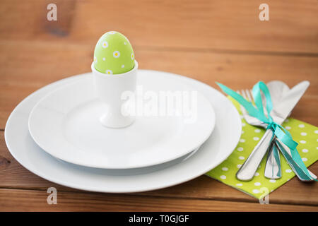 Oeuf de Pâques dans le porte-gobelet, assiettes et couverts Banque D'Images