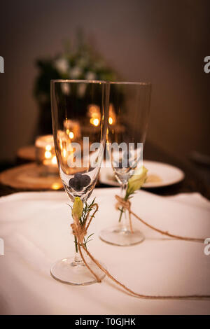 Deux verres de champagne sont vides contenant des bleuets sauvages de la forêt, sont décorées avec des fleurs jaunes et attaché avec une chaîne rustique, d'une bo Banque D'Images