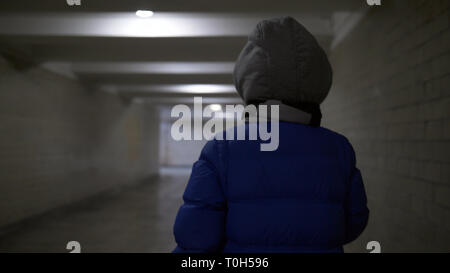 Adolescents promenades à travers un étroit tunnel sombre en hiver, tient quelque chose dans sa main, vue arrière Banque D'Images