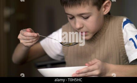 Garçon avec un appétit mange de la soupe, s'amuser Banque D'Images