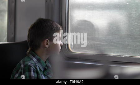 Garçon repose sur un train dans la soirée s'ouvre la fenêtre Banque D'Images