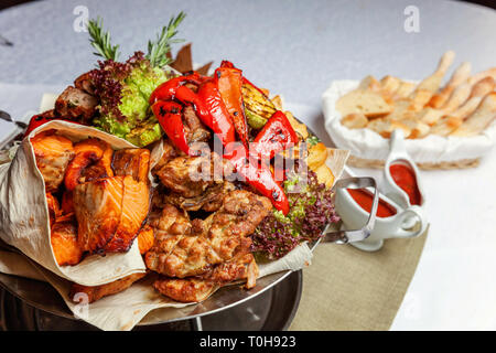 Grillade de viande, légumes et filets de poisson grillés, décoration à plat chaud. Un assortiment de délicieux kebab grillé servi avec des herbes sur plat Banque D'Images