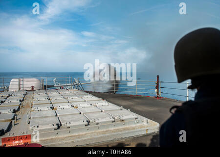 190311-N-AA191-0109 de l'OCÉAN ATLANTIQUE (11 mars 2019) Un marin regarde un cinq pouces canon est tiré pendant une démonstration de tir réel à bord du croiseur lance-missiles USS Hue (CG 66). La ville de Hue était en cours pour une croisière où les amis et les familles de l'équipage est monté à bord de l'expérience de la vie sur un croiseur. (U.S. Photo par marine Spécialiste de la communication de masse 2e classe Omar A. Diaz.) Banque D'Images