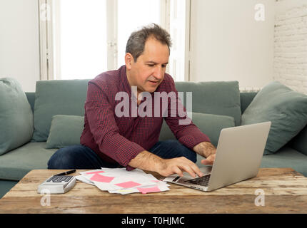 Homme séduisant mature sur ordinateur à la contrainte et inquiet avec les paiements par carte de crédit et les finances du foyer Les coûts comptables des impôts et des frais d'hypothèques Banque D'Images