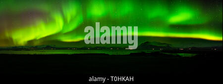 Un large panorama de la northern lights sur les montagnes en West-Iceland, reflétée dans la mer Banque D'Images