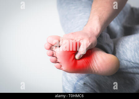 Homme Causian détient les mains pour ses pieds douloureux, des douleurs à pied. couleur rouge est domaine de la douleur Banque D'Images