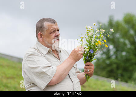 Plein air positif portrait of senior man with bouquet de fleurs sauvages pour sa femme Banque D'Images