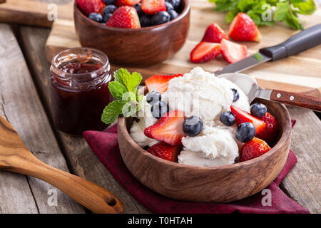 Bol en bois de crème glacée à la vanille avec les bleuets et les fraises sur une table en bois rustique Banque D'Images