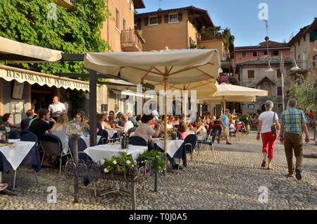 Malcesine, Italie - 7 août 2014 : les gens à l'extérieur terrasse de restautant en place pavée dans le village de Malcesine, l'établissement le plus au nord Banque D'Images