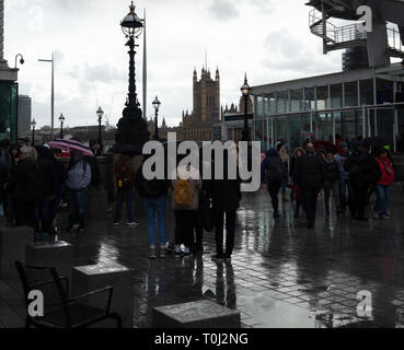 Touristes utilisent des parapluies et autres couvertures de pluie pour rester sec et humide sur ce jour humide sur la rive sud au pied du London Eye à Londres, au Royaume-Uni. Banque D'Images