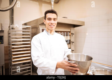 Jeune homme aux yeux sombres se sentir heureux travaillant en bonne boulangerie Banque D'Images