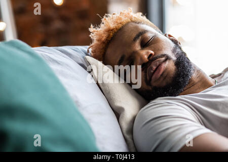 Beau jeune homme agréable de dormir sur son lit Banque D'Images