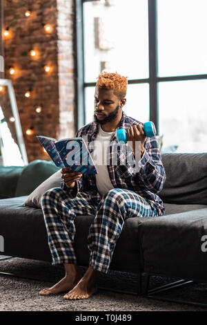 Homme agréable sérieux l'entraînement avec un haltère Banque D'Images