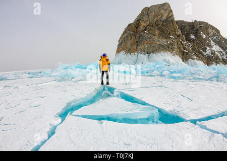 L'homme se tient près du cap Khoboy rock sur l'île d'Olkhon, le lac Baïkal, la glace de buttes en hiver, de la Russie, de la Sibérie Banque D'Images