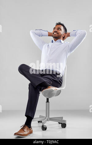 Smiling indian businessman sitting on office chair Banque D'Images