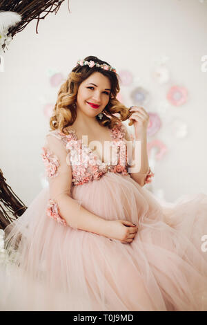 Pregnant woman sitting on grand couronne de vigne décoré. Banque D'Images