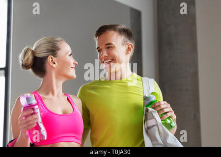 Couple sportif avec des bouteilles d'eau et de sport dans un sac Banque D'Images