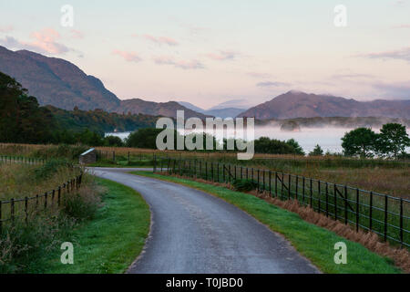 Paisible tôt le matin vue tranquille sur les montagnes avec allée et brouillard à Castleough Bay, lac Lough Leane dans le parc national de Killarney, comté de Kerry, Irlande Banque D'Images