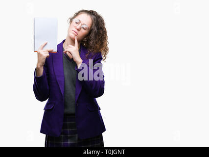 Jeune étudiante brunette girl wearing school uniform tenant un ordinateur portable isolé sur fond visage sérieux de penser à question, ide très confus Banque D'Images