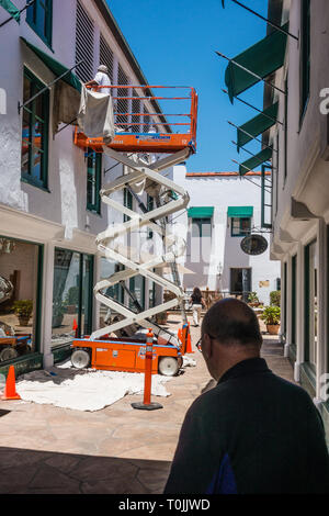 Deux peintres, un bâtiment commercial de stuc blanc ciseaux à l'aide d'un ascenseur et d'une échelle midi à Santa Barbara, en Californie. Banque D'Images