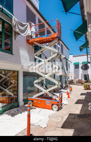 Deux peintres, un bâtiment commercial de stuc blanc ciseaux à l'aide d'un ascenseur et d'une échelle midi à Santa Barbara, en Californie. Banque D'Images