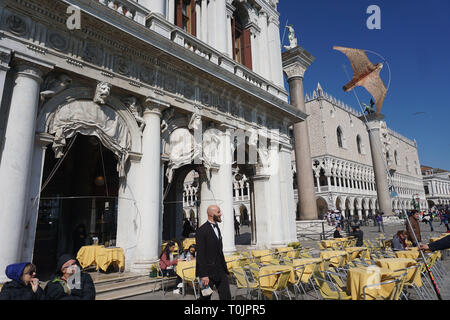 Venise, Italie. Mar 20, 2019. Le cerf-volant qui ressemble à un faucon tout en tournant autour de la tables du cafe Todaro, à la place San Marco, à effrayer les mouettes le 20 mars 2019 à Venise, Italie. Mouettes affamées n'hésitez pas à attaquer les touristes, pour voler des sandwiches ou des apéritifs, tandis qu'ils ont un verre assis à la tables des cafés de la place San Marco. Credit : Andrea Merola/éveil/Alamy Live News Banque D'Images