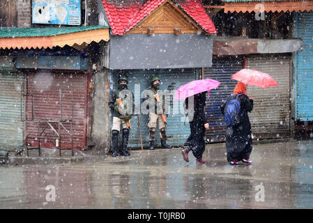 Srinagar, Jammu-et-Cachemire, en Inde. Mar 20, 2019. Les femmes du Cachemire sont vus marcher passé paramilitaires indiennes montent la garde au milieu de neige en une mise à l'arrêt à Srinagar.vit en vallée du Cachemire le mercredi en raison d'un arrêt de protestation appelé par les séparatistes contre la peine mort d'un enseignant de l'école hier. En nombre suffisant des Forces canadiennes ont été déployés dans les zones sensibles pour contrecarrer toute protestation en vue de l'appel d'arrêt émis par le seperatists. Credit : Idrees Abbas/SOPA Images/ZUMA/Alamy Fil Live News Banque D'Images