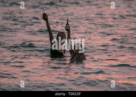 Adélaïde, Australie. Mar 21, 2019. Les nageurs dans les eaux de l'océan porter un toast avec des bouteilles de bière comme le coucher de soleil sur plage de Grange à Adélaïde : Crédit amer ghazzal/Alamy Live News Banque D'Images