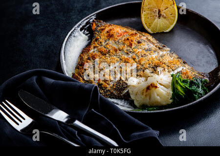 Filet de flétan rôti dans une poêle avec des herbes et du citron Banque D'Images