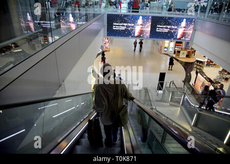 Angleterre Heathrow Airport Terminal 2 passager sur Escalator avec valise en direction de Departure Lounge Banque D'Images