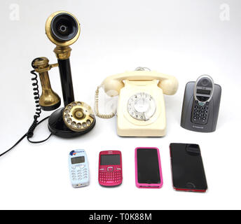 Une collection de téléphones anciens et nouveaux - Chandelier téléphone, téléphone à cadran rotatif, téléphone sans fil et mobiles - Nokia 3310, Nokia C3, l'iPhone 5 Banque D'Images