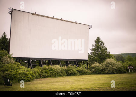 Drive-in theatre écran de cinéma se trouve dans la distance ; entourée d'herbe et de l'excroissance boisée. Banque D'Images