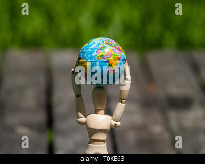 Un mannequin en bois avec un ballon dans ses bras. Concept de l'écologie, la mondialisation Banque D'Images