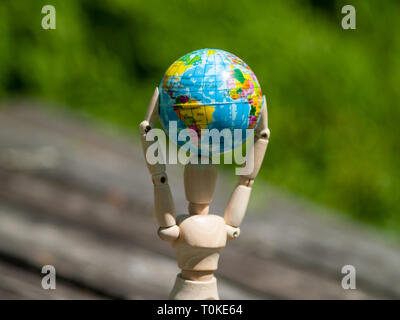 Un mannequin en bois avec un ballon dans ses bras. Concept de l'écologie, la mondialisation Banque D'Images